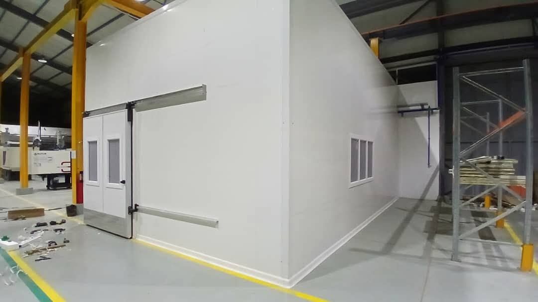 Salle fermée en panneaux lisses construite autour d'une machine de production