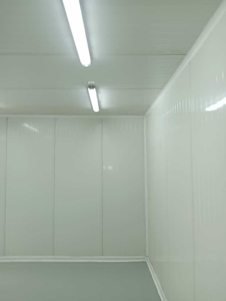 Intérieur d'une salle blanche : panneaux lisses, plinthes arrondies et éclairage étanche